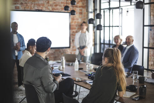 Weibliche und männliche Kollegen diskutieren mit Investoren bei einem Treffen im Büro - MASF25303