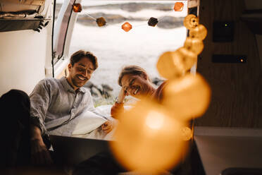 Happy gay couple using laptop in motor home during vacation - MASF25317