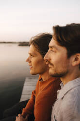 Homosexuelles Paar schaut weg, während es seine Freizeit am Seeufer verbringt - MASF25325