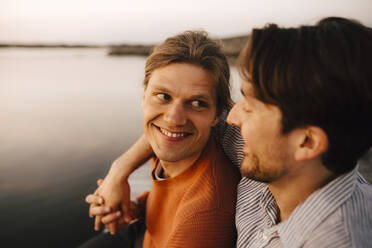 Smiling man with arm around of boyfriend by lake - MASF25326