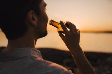 Mann mit Bierflasche bei Sonnenuntergang - MASF25335