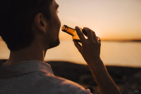 Man with beer bottle during sunset - MASF25335