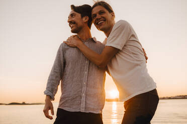 Portrait of smiling man standing by boyfriend against lake - MASF25336