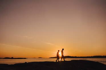 Gay couple spending leisure time while walking during sunset - MASF25341