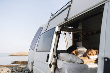 Man relaxing in camping van at lakeshore - MASF25374