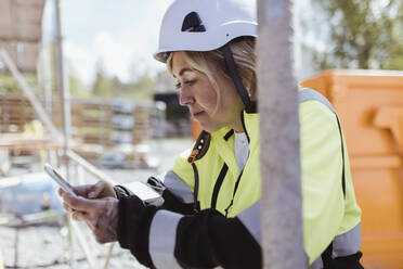 Female building contractor using smart phone at construction site - MASF25398