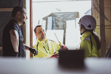 Männliche und weibliche Bauarbeiter diskutieren gemeinsam auf der Baustelle - MASF25411