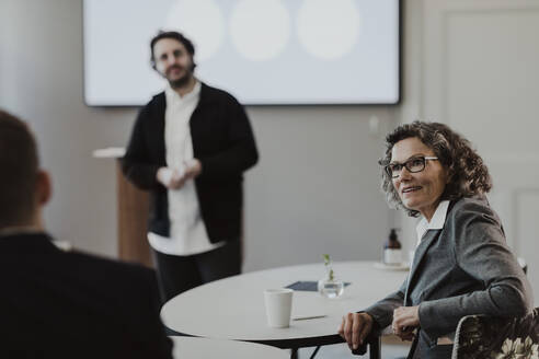 Businessman giving presentation while male and female colleagues discussing in office - MASF25514