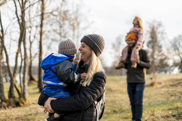 Cheerful mother carrying son while standing at park - MASF25519