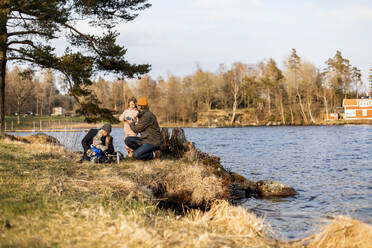 Mittlerer erwachsener Mann und Frau mit Kindern am See im Park - MASF25521