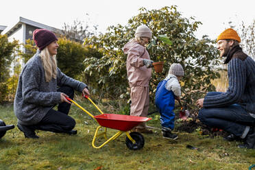 Glückliche Familie bei der gemeinsamen Gartenarbeit im Hinterhof - MASF25544