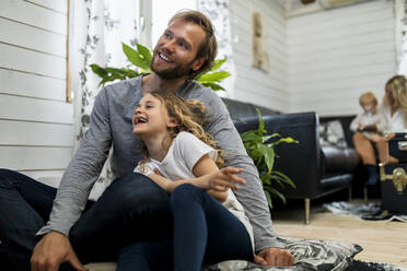 Fröhliche Tochter sitzt mit ihrem Vater im heimischen Wohnzimmer - MASF25553