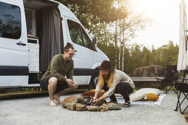 Male friends preparing campfire by motor home - MASF25624