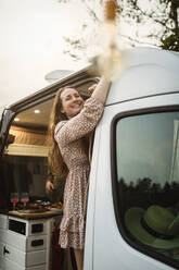 Smiling woman looking away while standing in motor home - MASF25628