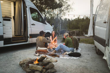 Happy male and female friends camping by motor home - MASF25630
