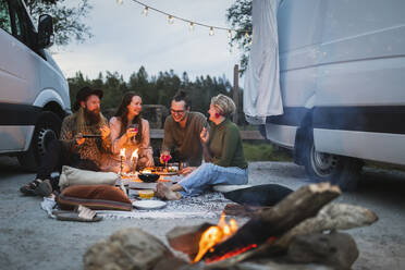 Smiling male and female friends spending leisure time by motor home - MASF25635