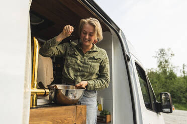 Lächelnde Freundin, die beim Kochen im Wohnmobil Salz streut - MASF25656