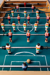Detailaufnahme eines Retro-Tischfußballs mit hölzernen Miniaturfiguren von Spielern auf Metallstangen - ADSF29972
