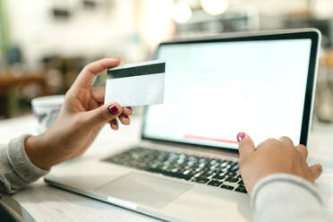 Crop unrecognizable female making purchase with plastic card for order during online shopping via laptop - ADSF29982