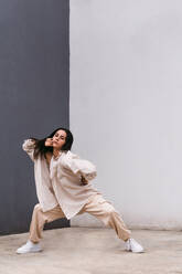 Talented female dancer moving and dancing near concrete wall in urban area in city looking at camera - ADSF30001