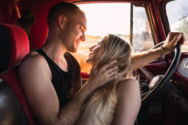 Loving couple looking at each other in vintage car parked in nature on sunny day - ADSF30013