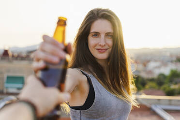 Lächelnde Frau nimmt Bierflasche von Freund auf Dachterrasse - AFVF09181