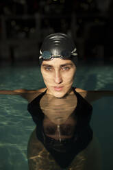 Young beautiful woman in the indoor pool, wearing black swimsuit, look at camera - ADSF30186