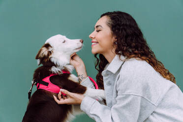 Slide view of female looking away owner caressing Border Collie dog on leash while both are sitting - ADSF30240