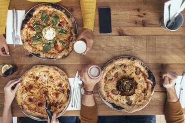 Männliche und weibliche Freunde sitzen mit Pizza am Tisch im Restaurant - JSRF01586