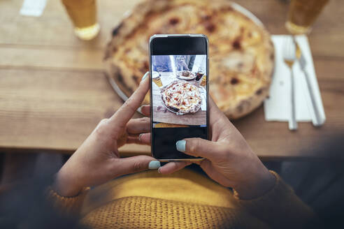 Junge Frau fotografiert Pizza mit ihrem Smartphone - JSRF01589