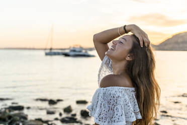 Young woman with eyes closed standing at beach - DLTSF02156