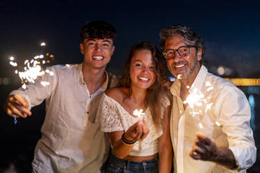 Familie genießt Wunderkerzen am Strand bei Nacht - DLTSF02181