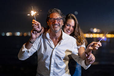 Father with daughter holding sparklers at night - DLTSF02182