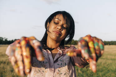 Mid adult woman with paint on hands at park - ASGF01518