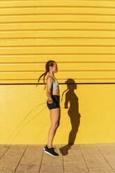 Female athlete doing skipping while practicing on footpath during sunny day - MGRF00443