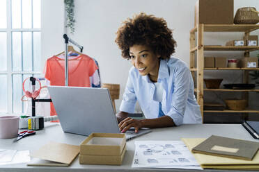 Female fashion designer using laptop while working at studio - GIOF13456