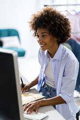 Smiling female entrepreneur using desktop computer while working at studio - GIOF13483
