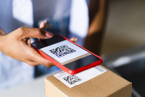 Woman scanning barcode on package at studio - GIOF13497