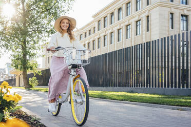 Lächelnde Frau beim Fahrradfahren auf dem Fußweg - VPIF04850