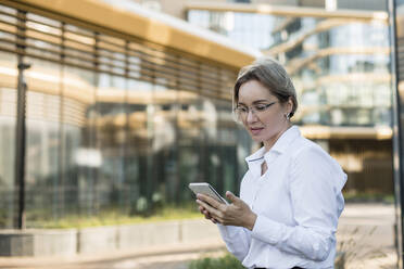 Geschäftsfrau mit Brille und Mobiltelefon - LLUF00071