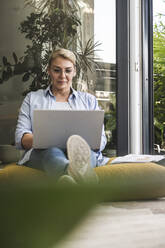 Geschäftsfrau benutzt Laptop, während sie zu Hause sitzt - UUF24695