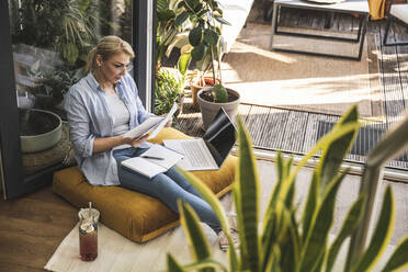 Female freelancer checking document while working at home - UUF24700