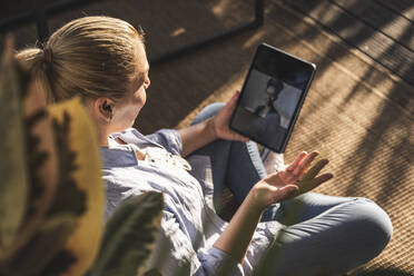 Woman talking with friend on video call through digital tablet on terrace - UUF24708