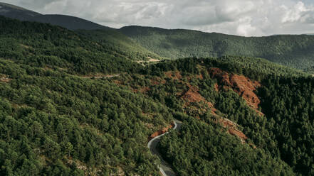 Luftaufnahme einer kurvenreichen Straße, die sich durch die bewaldete Landschaft der Pyrenäen zieht - OCAF00750