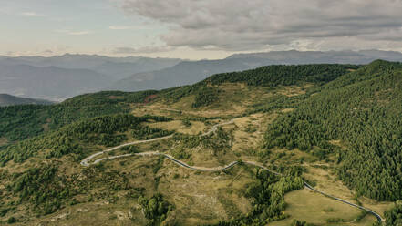 Luftaufnahme einer Landstraße, die sich durch die bewaldete Landschaft der Pyrenäen zieht - OCAF00758
