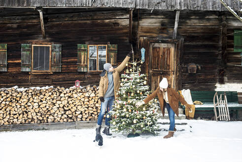 Junges Paar beim Schmücken des Weihnachtsbaums im Winter - HHF05660