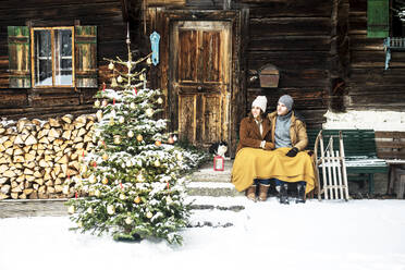 Couple looking at Christmas tree while sitting in front of farmhouse - HHF05663