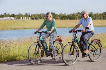 Couple riding bicycle together on road during sunny day - AANF00012