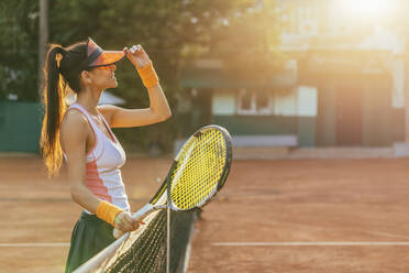 Tennisspielerin mit Schläger am Netz auf einem Sportplatz - OYF00502