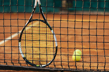 Tennisschläger und Ball am Netz auf einem Sportplatz - OYF00505